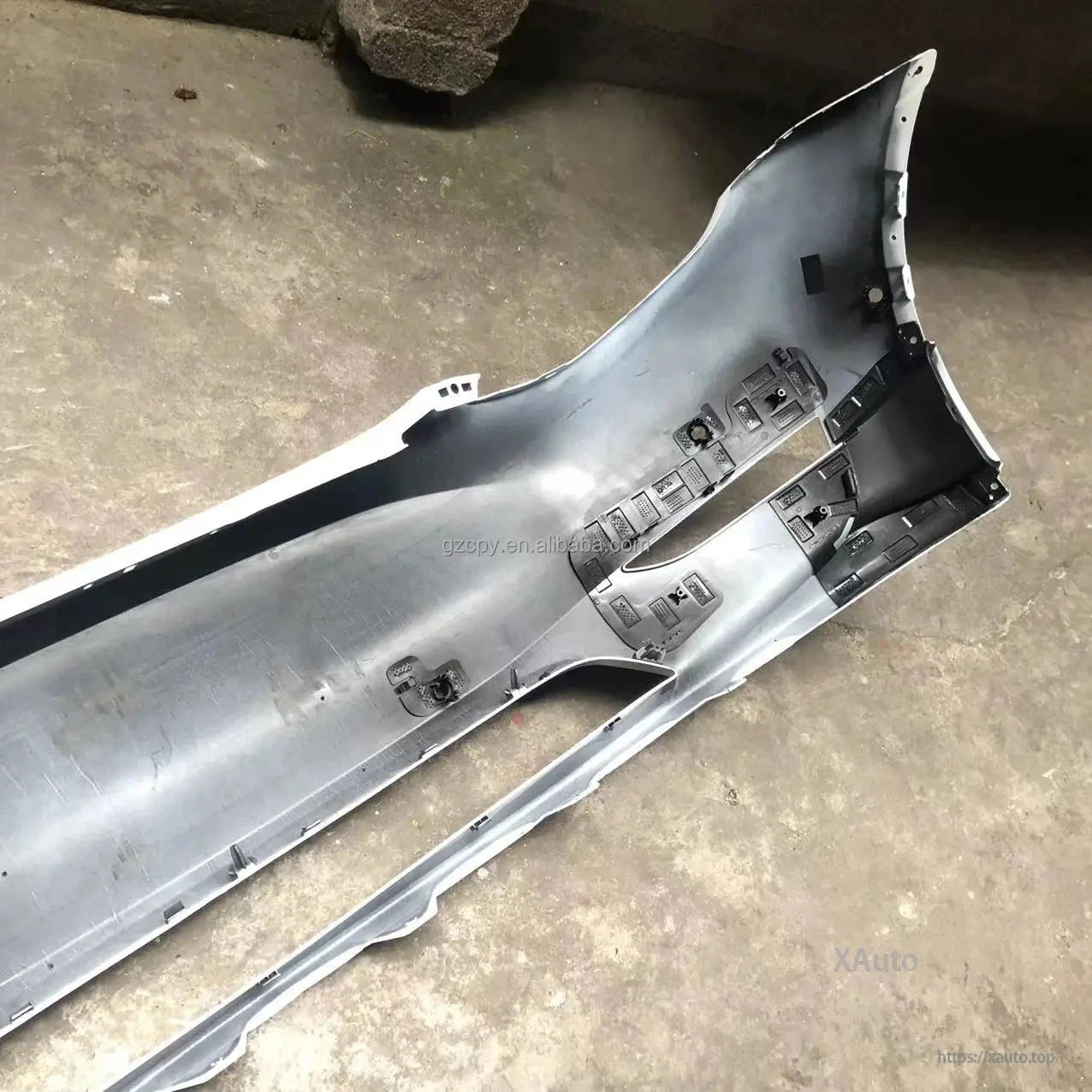 Backside close-up of bumper cover end showing reinforcement ribs, brackets, and fastener points