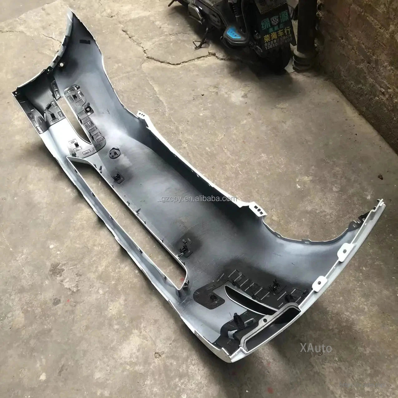 Full backside view of bumper cover on floor showing mounting points across the entire panel